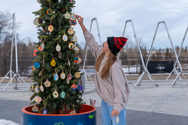 Girl hanging ornaments on Kindness Tree